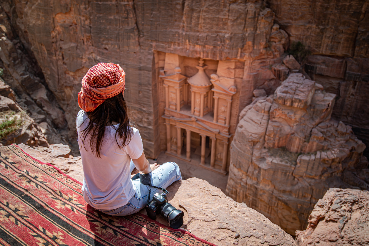 Femme assise face à la cité de Petra en Jordanie